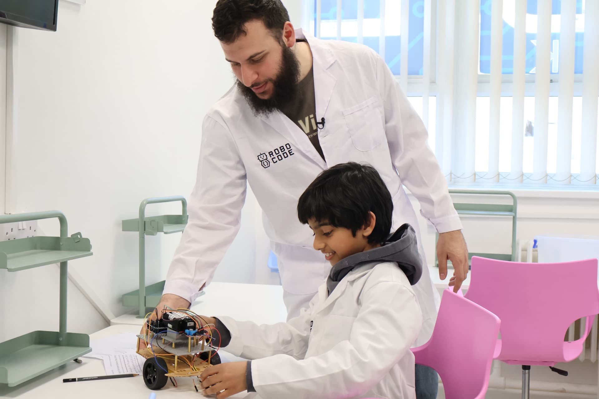 Instructor and student examining a completed robot car at Robocode